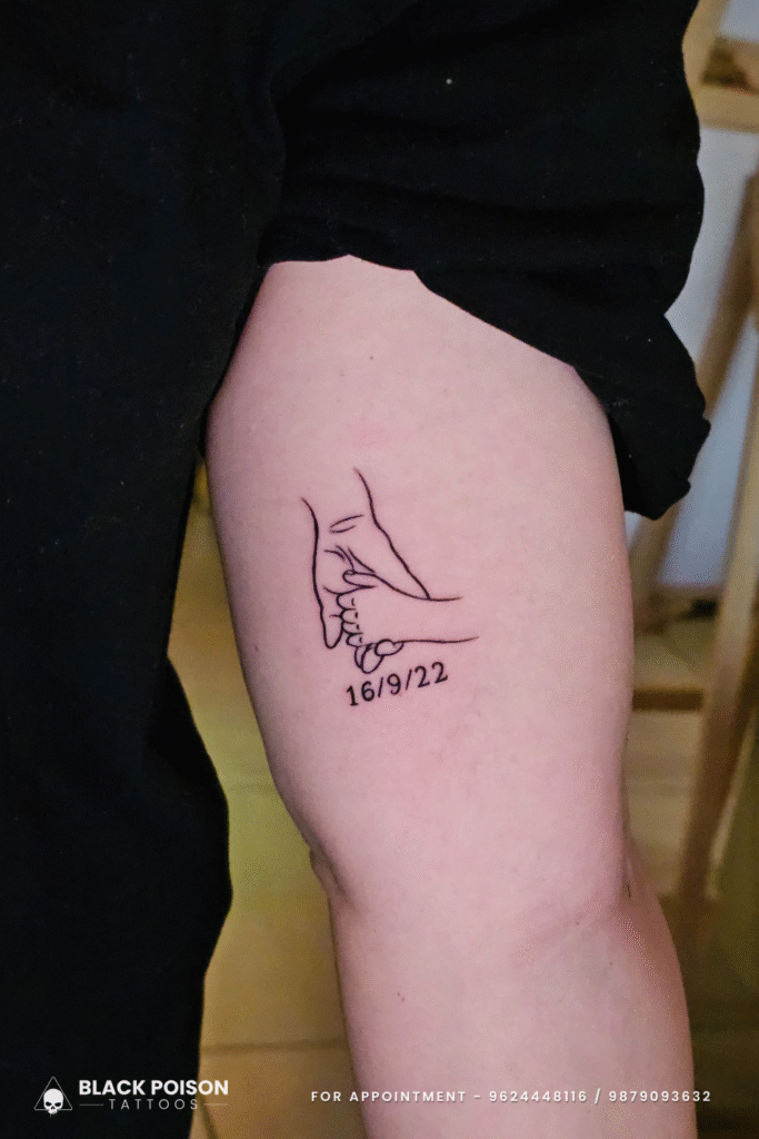 Minimalist holding hands birth date tattoo on upper arm