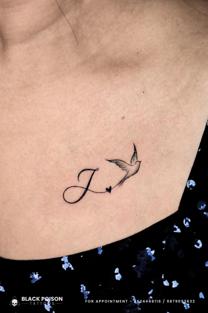 Minimalist small bird and initial letter tattoo on collarbone