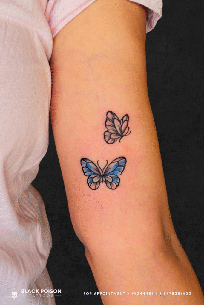 Twin butterfly tattoo on arm with blue and black shading