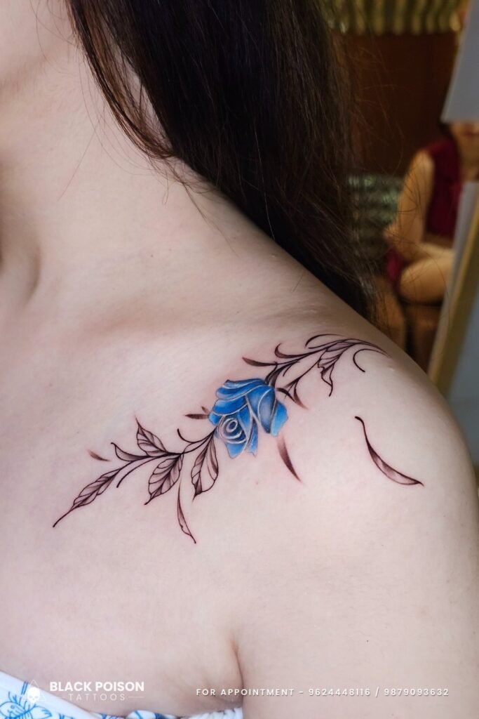Blue rose tattoo with fine line leaves on collarbone