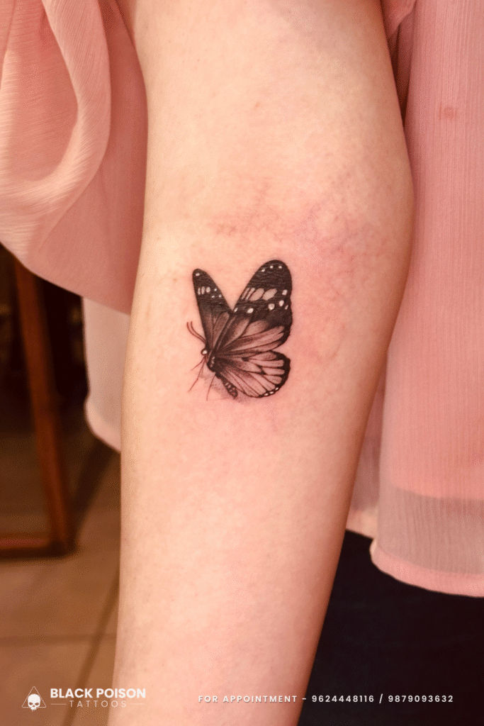 Realistic black and grey butterfly tattoo on forearm by Black Poison Tattoos Ahmedabad
