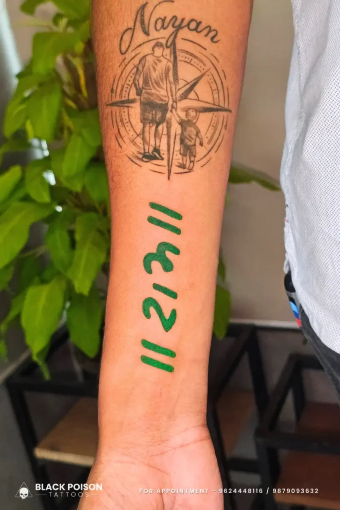 A meaningful tattoo featuring the "Ram" mantra in bold green Sanskrit script below a fine-line silhouette of a father and son walking toward a compass by Black Poison Tattoo Studio Ahmedabad.