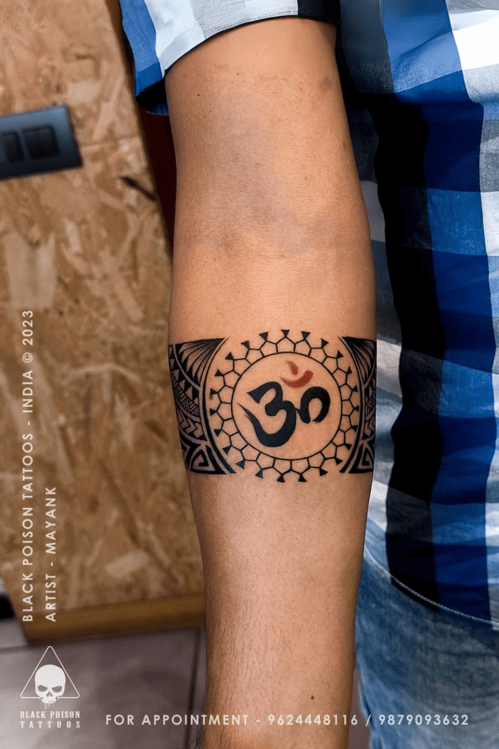 Armband tattoo with an Om symbol and mandala dot work pattern on the forearm
