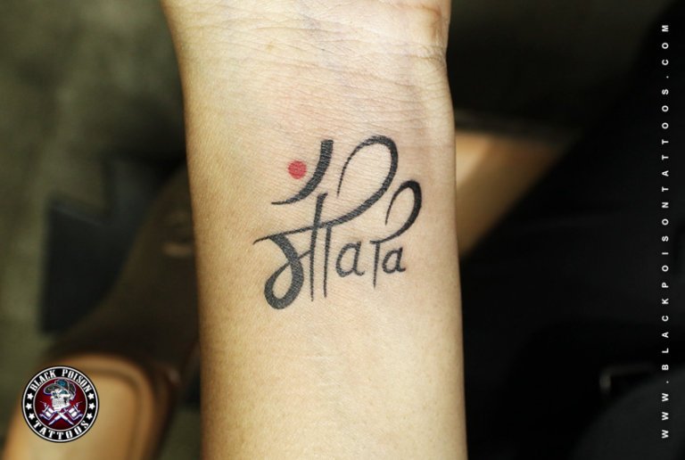 Maa tattoo in Devanagari script with a red dot on the wrist