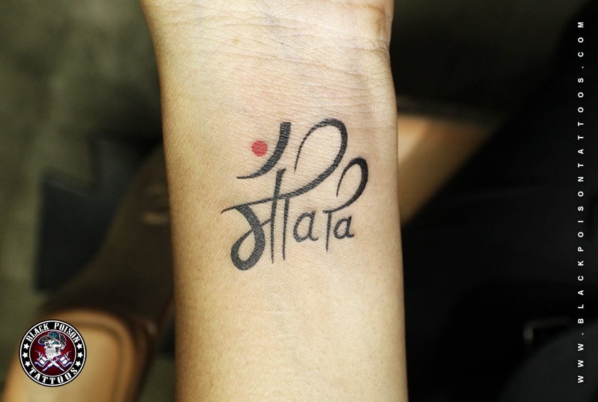 Maa tattoo in Devanagari script with a red dot on the wrist