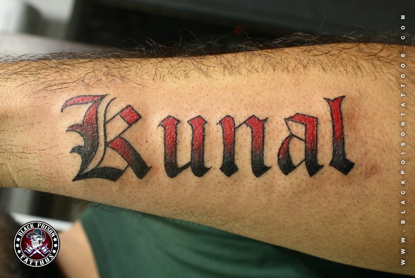 Bold gothic name lettering tattoo in red and black on the forearm
