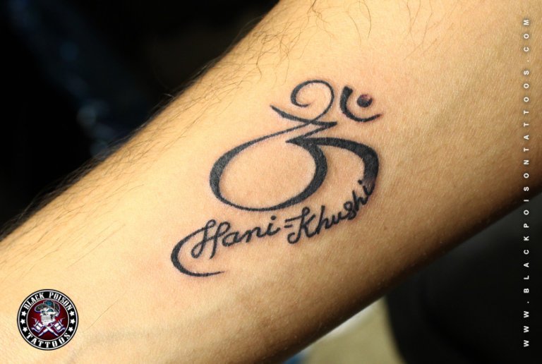 Om symbol tattoo with script lettering on the forearm