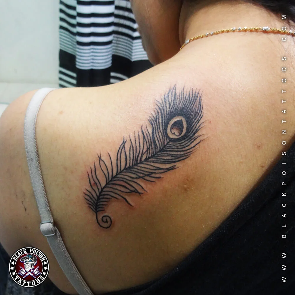 Black feather tattoo on shoulder for women
