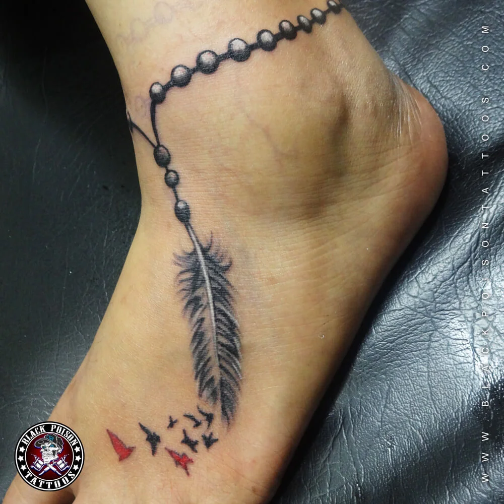 Feather anklet tattoo with beads and small red birds on the ankle