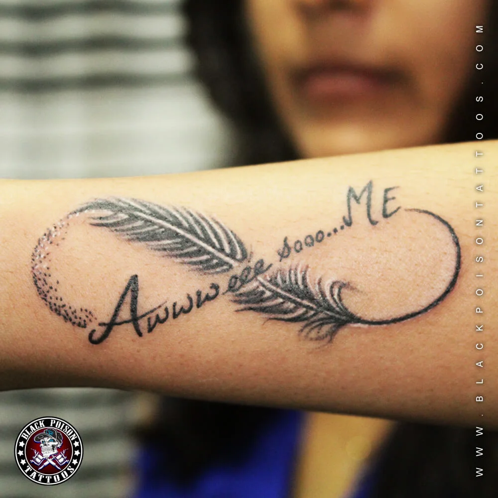 Infinity feather tattoo with handwritten script on the forearm