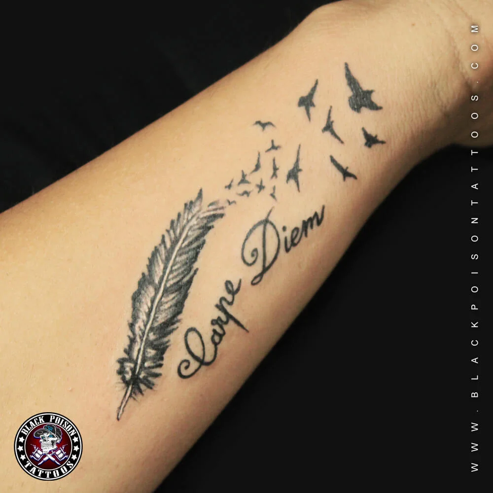 Feather tattoo with flying birds and Carpe Diem lettering on the forearm