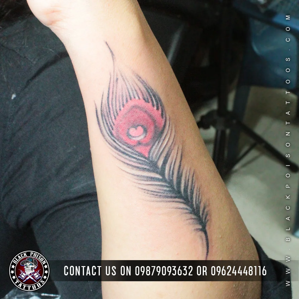 Black and grey feather tattoo with a pink eye on the upper arm