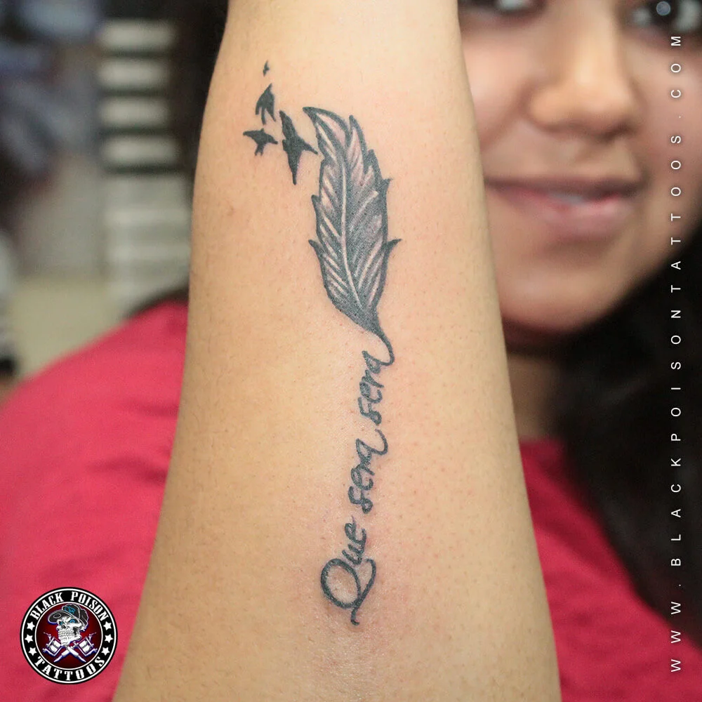 Fine line feather tattoo with birds and script lettering on the forearm