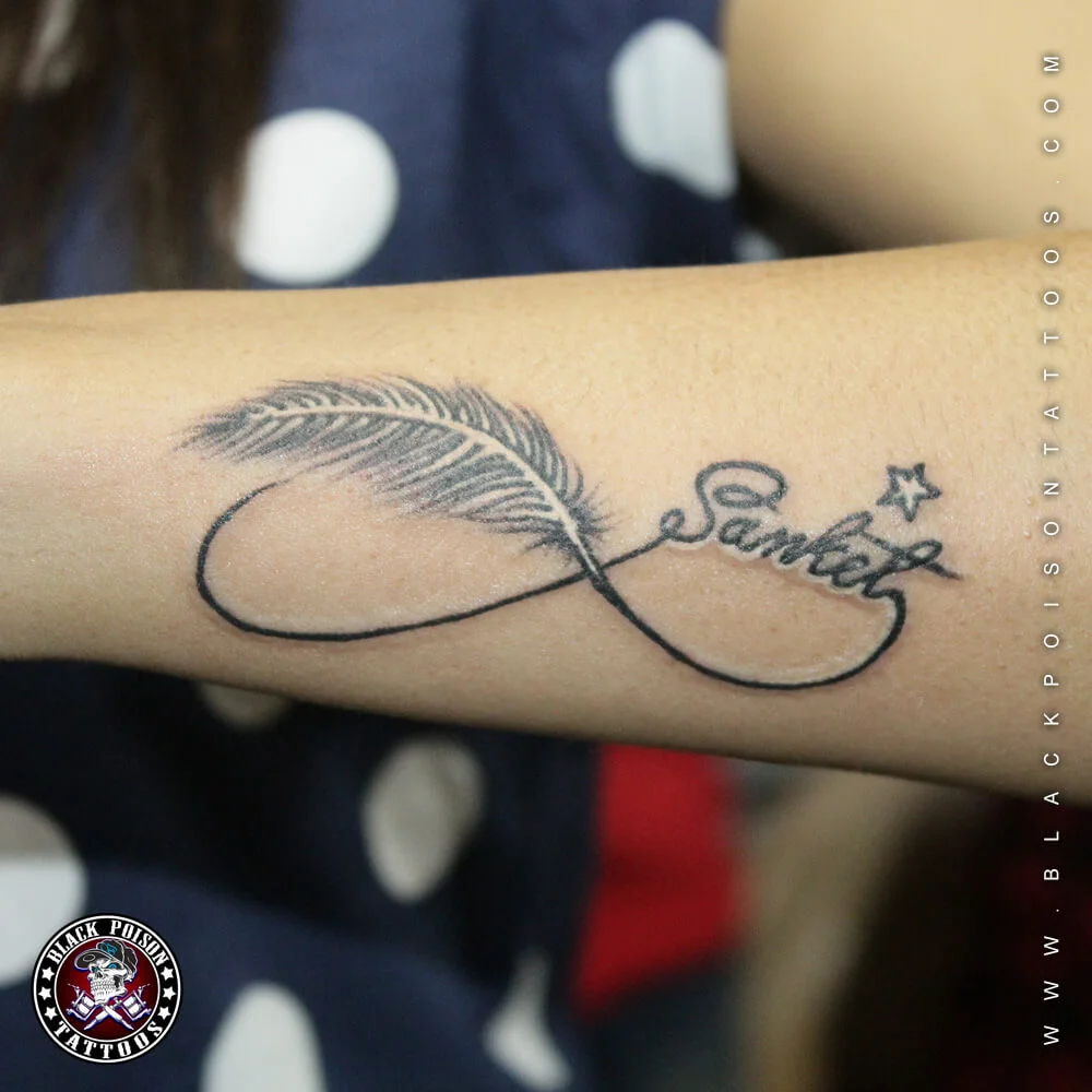 Fine line infinity feather tattoo with a name in script on the forearm