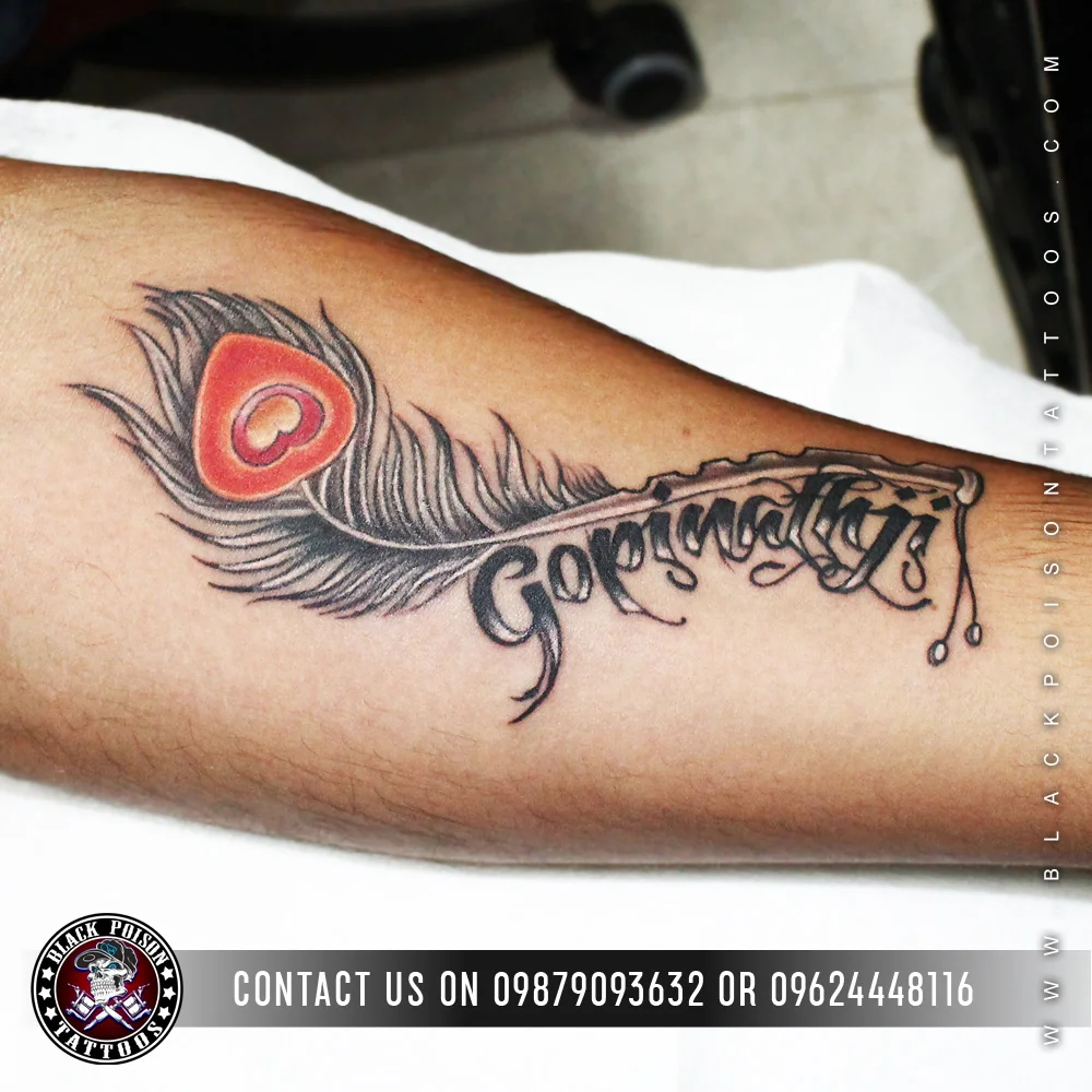 Feather tattoo with a red eye and Gopinath lettering on the forearm