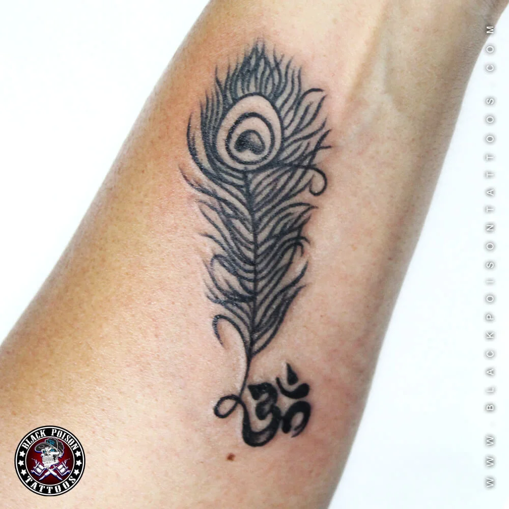 Peacock feather tattoo with Devanagari lettering at the base on the forearm