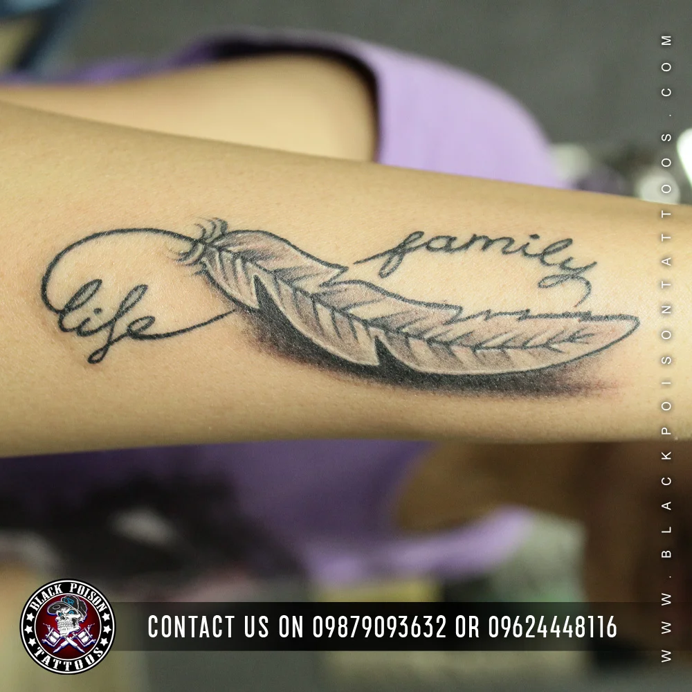Black and grey feather tattoo on the forearm with the words life and family in script