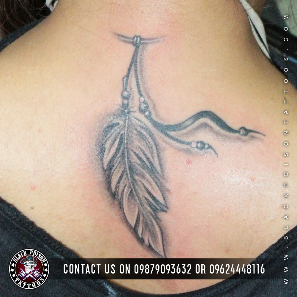 Two black and grey feather tattoos with hanging strings on the nape of the neck