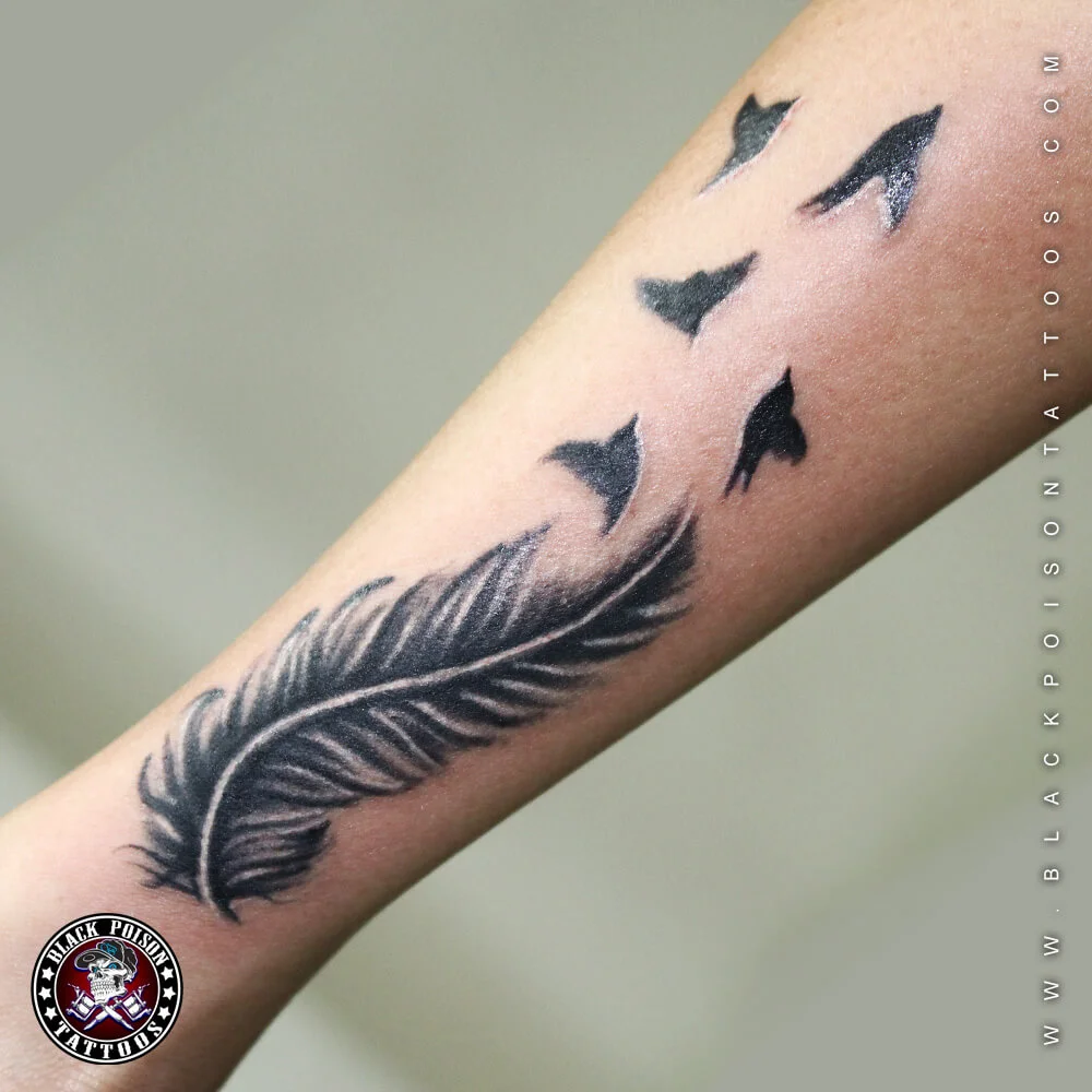 Feather tattoo with a flock of birds flying from it on the forearm