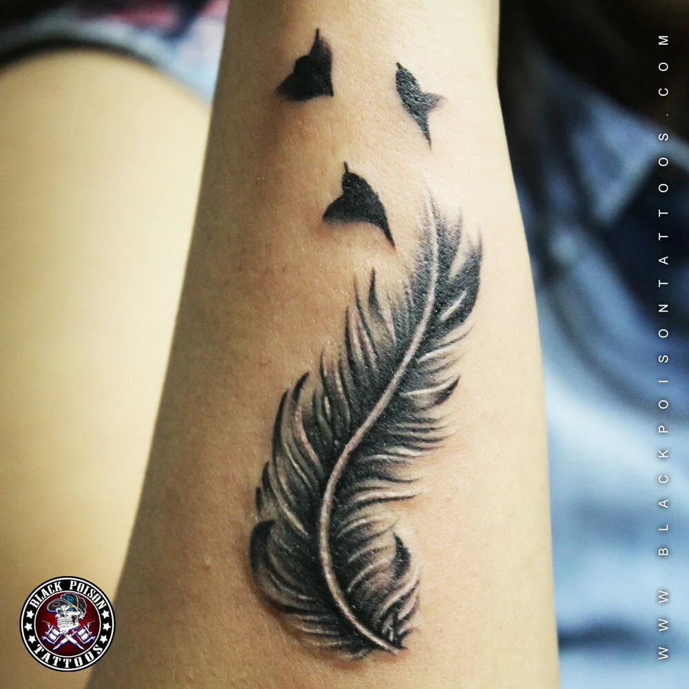Black and grey feather tattoo with birds flying upward on the arm