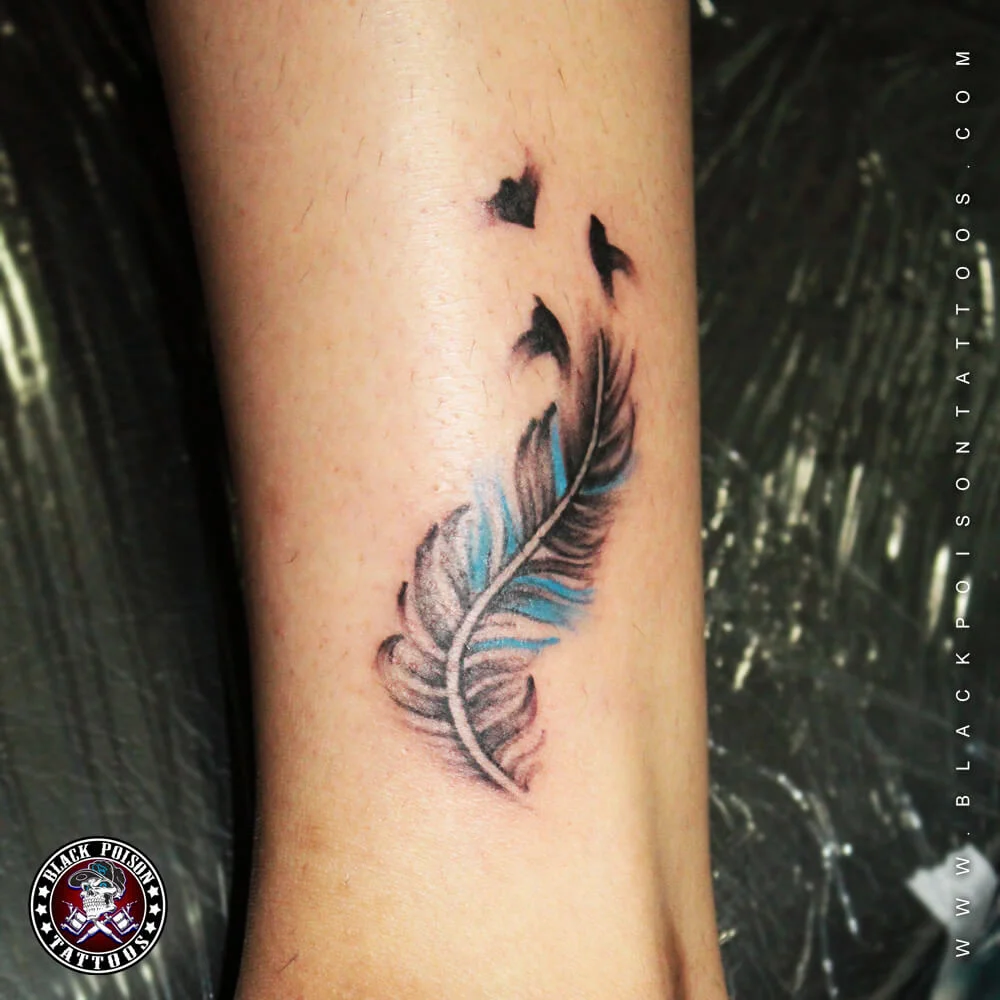 Small teal feather tattoo with birds on the forearm