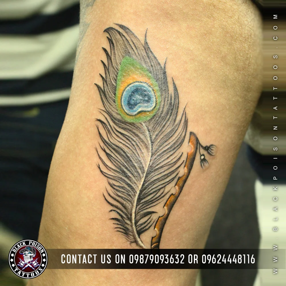 Coloured peacock feather tattoo with a flute on the upper arm