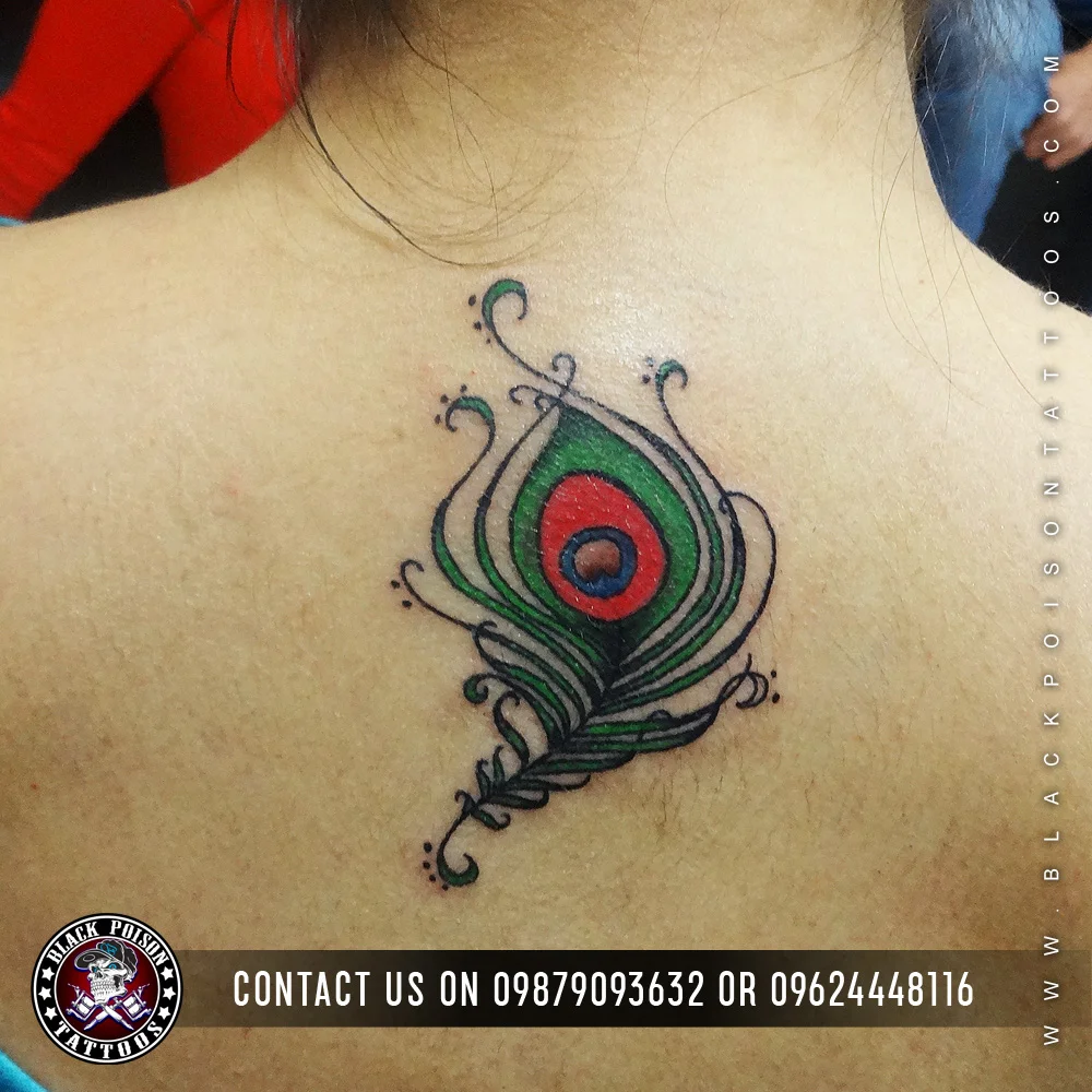 Colourful peacock feather tattoo with ornamental swirls on the upper back