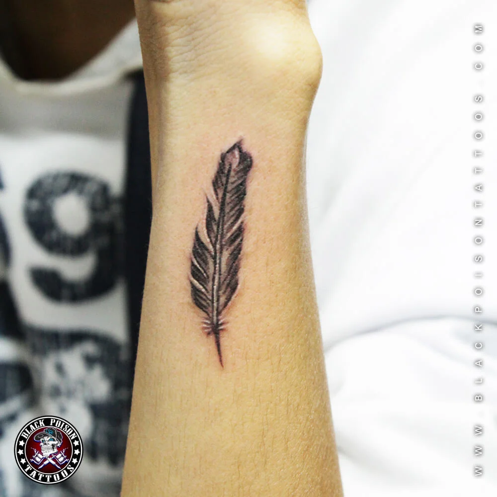 Small delicate feather tattoo on the inner forearm