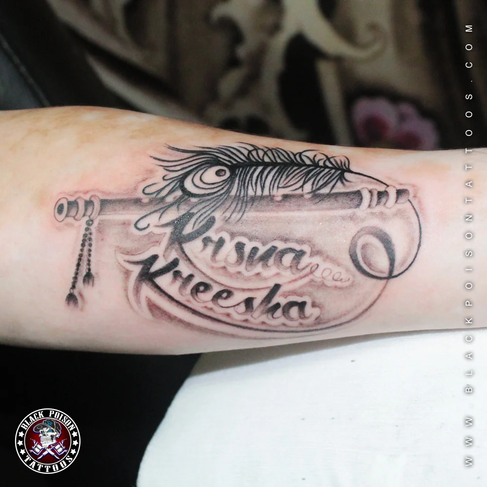 Ornamental feather and key tattoo with the names Krisha and Kheesha on the forearm
