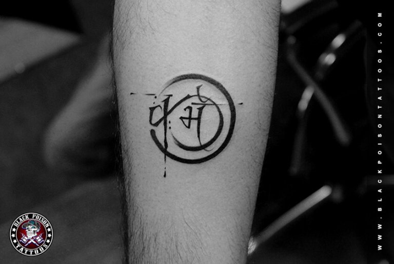 Circular emblem tattoo with Devanagari lettering on the forearm