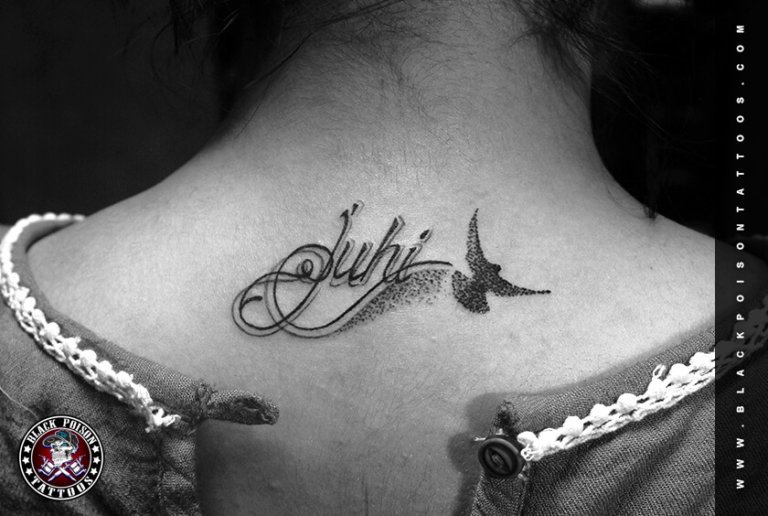 Script name tattoo with a small bird on the shoulder