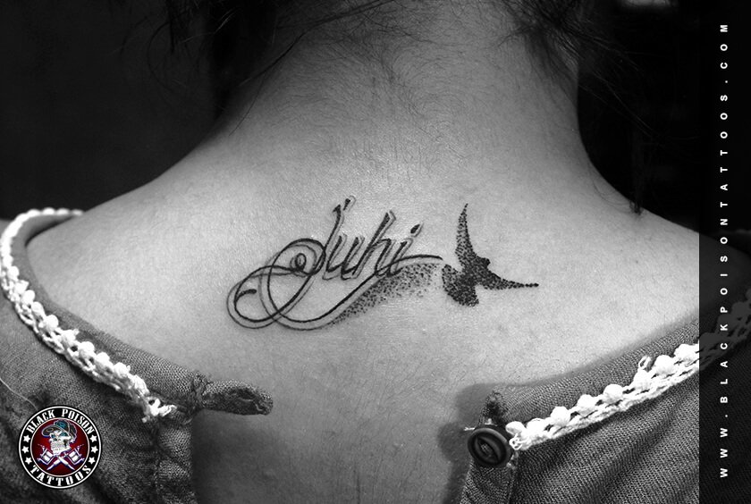 Script name tattoo with a small bird on the shoulder
