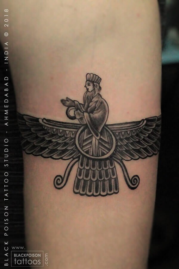 Black and grey Faravahar winged symbol tattoo on the forearm