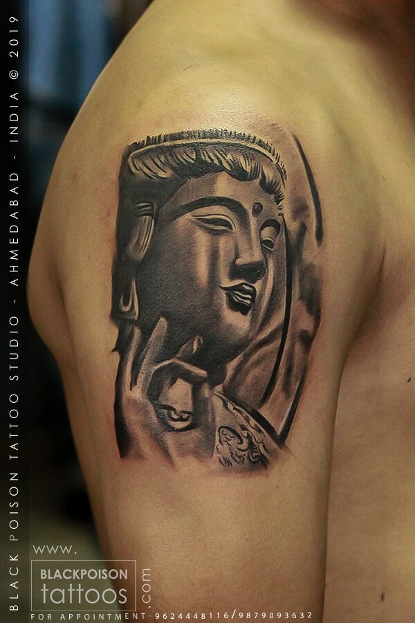Black and grey Buddha portrait tattoo on the upper arm