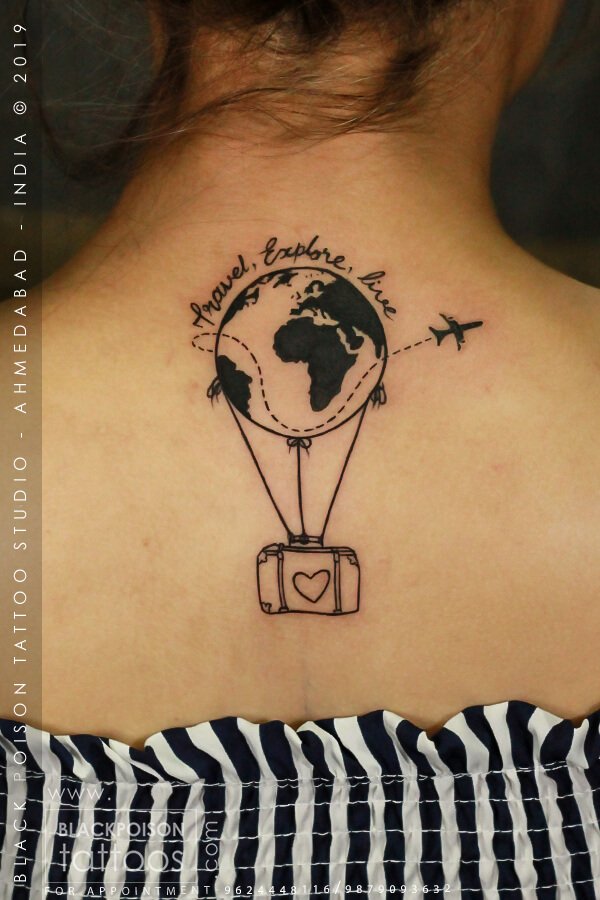Travel themed tattoo with a globe, hot air balloon and suitcase on the upper back