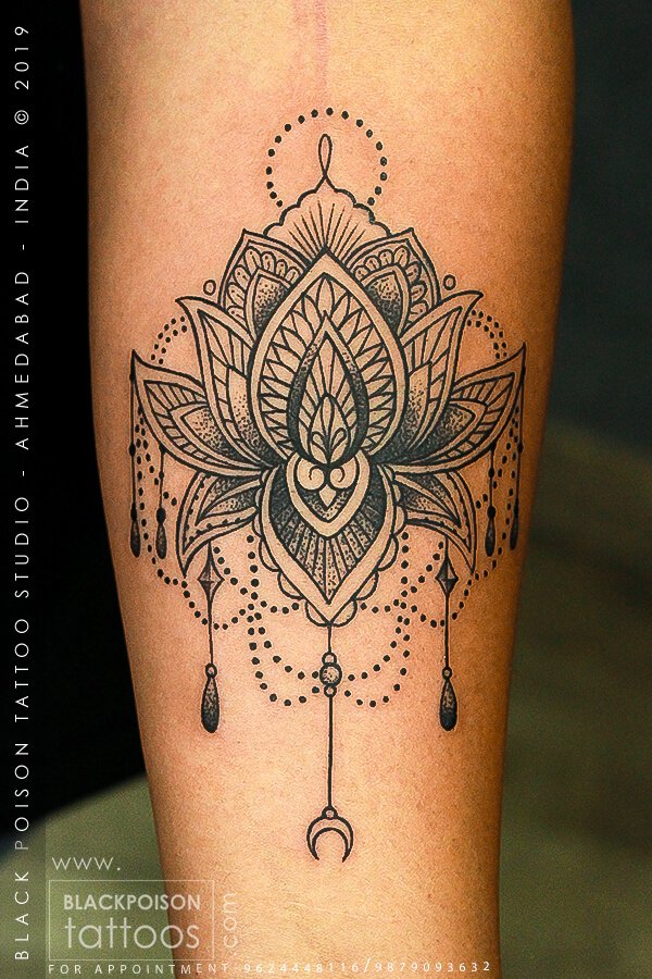 Ornamental lotus mandala tattoo with hanging chains and a crescent on the forearm