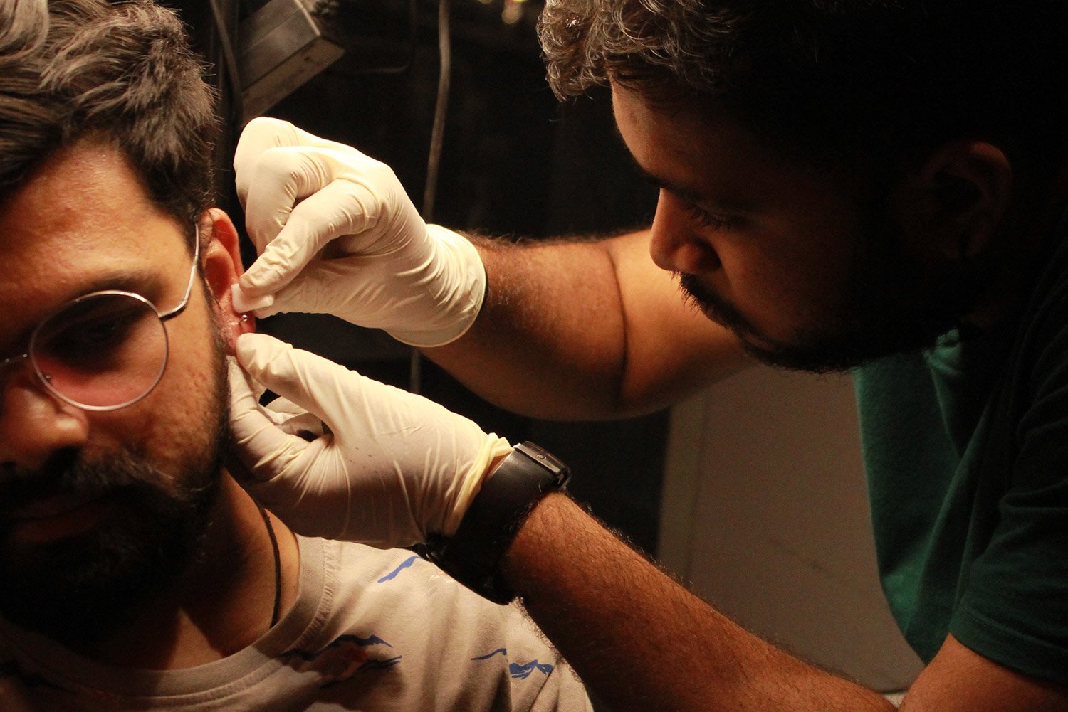 Piercer marking and performing an ear piercing on a client at the studio
