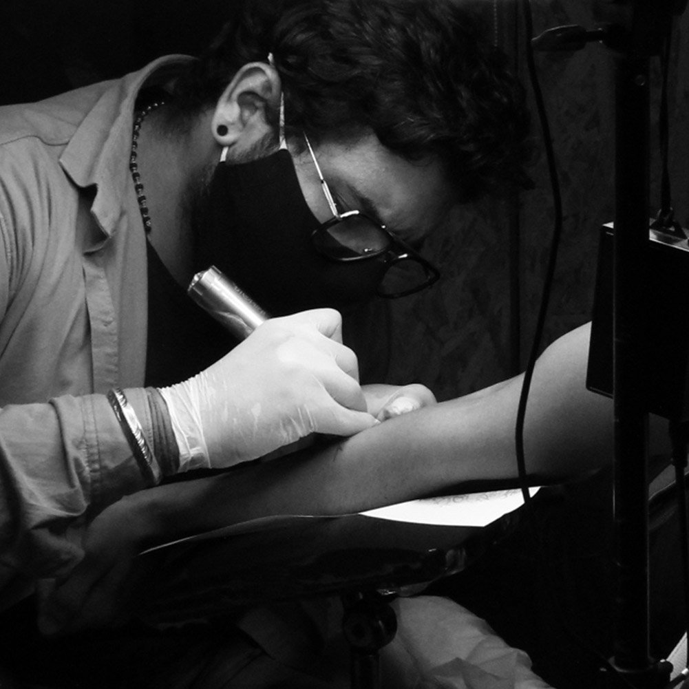 Tattoo artist working on a client's forearm at the studio