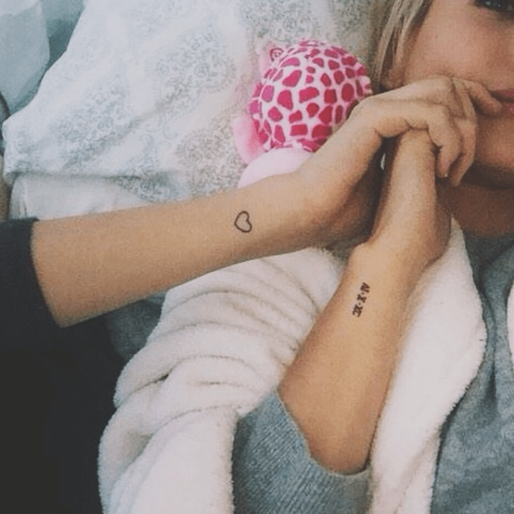 Close up of Hailey Baldwin's small wrist tattoos, a heart and a set of numbers