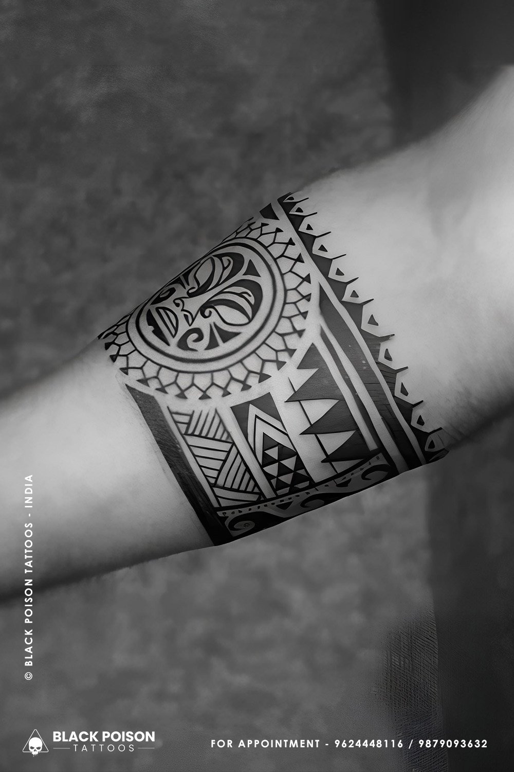 Blackwork Polynesian armband tattoo with tiki mask and geometric spearheads by Black Poison Tattoo Studio Ahmedabad