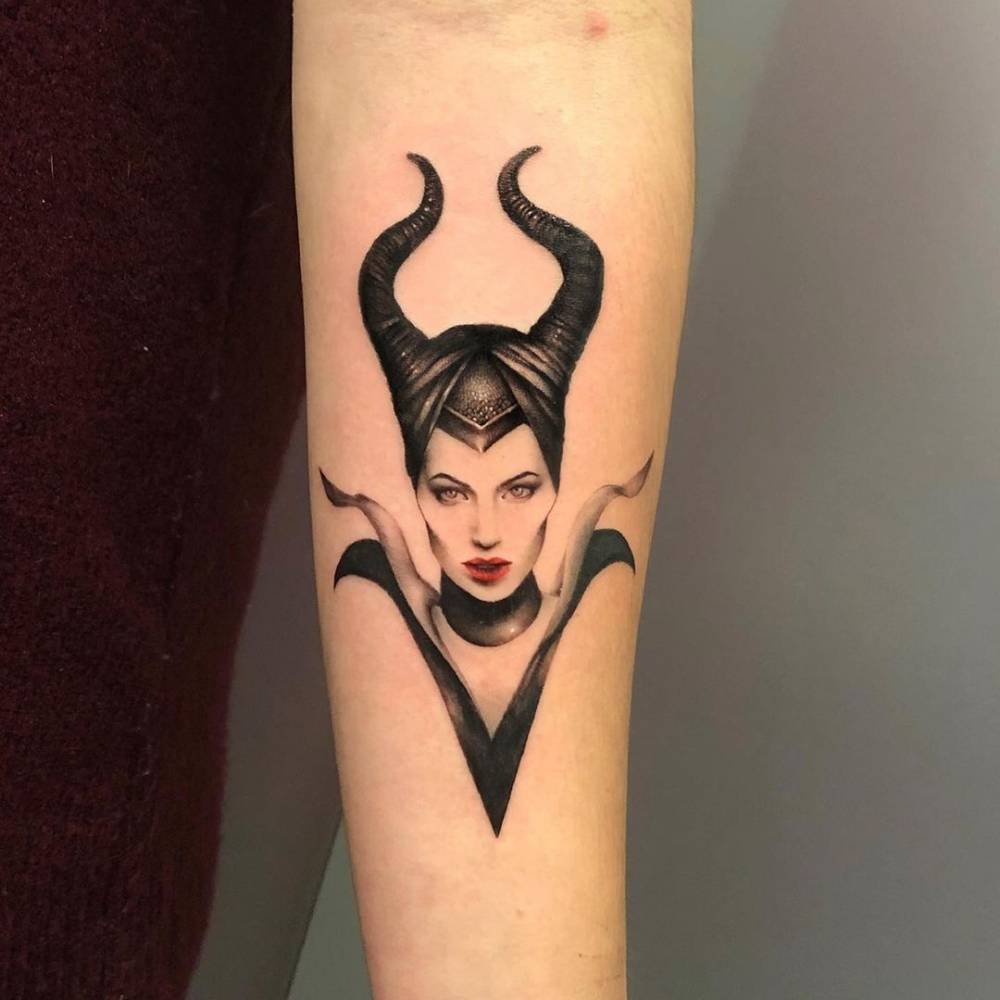 Black and grey Maleficent tattoo with horns and red lips on the forearm