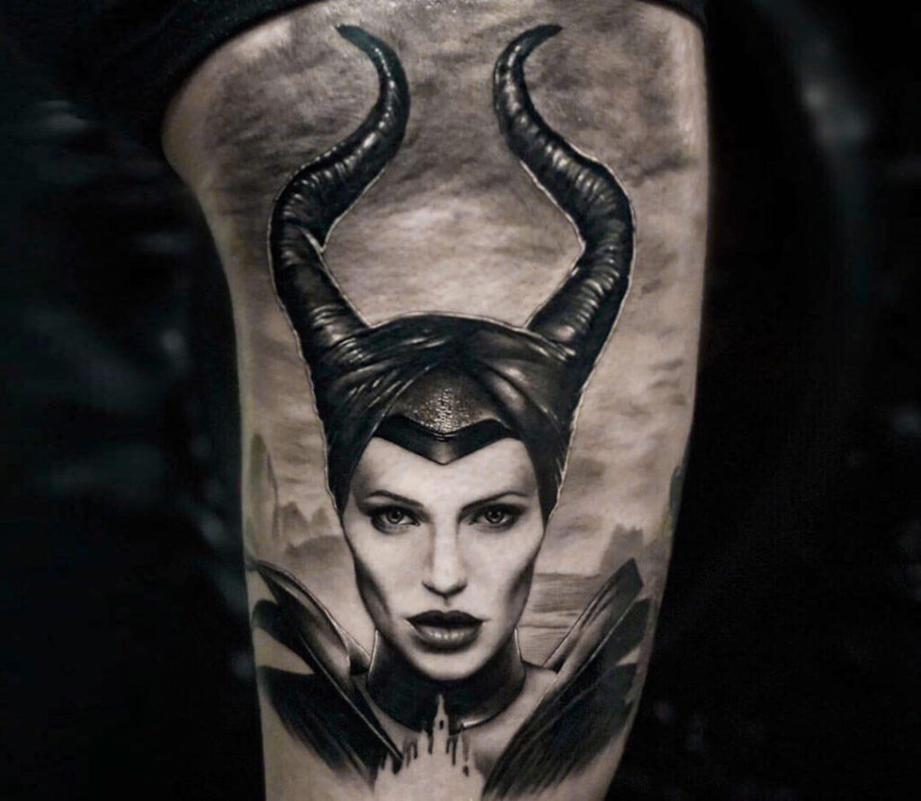 Realistic black and grey Maleficent portrait tattoo with large curved horns on the thigh