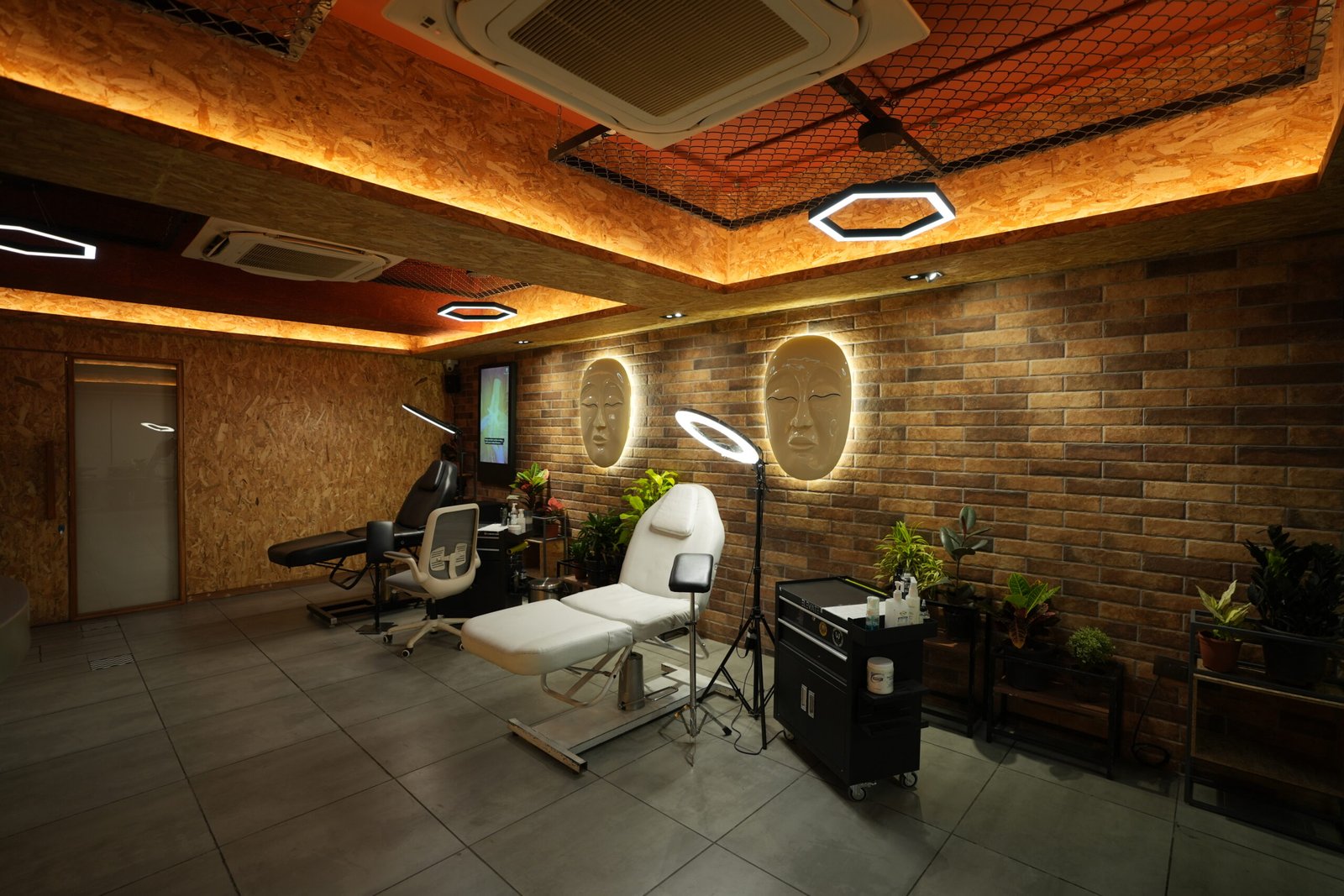 Treatment room at the studio with tattoo beds, ring lights and exposed brick walls