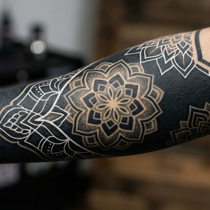 A deeply saturated, custom blackwork and blackout sleeve featuring negative space mandalas by Black Poison Tattoo Studio in Ahmedabad.