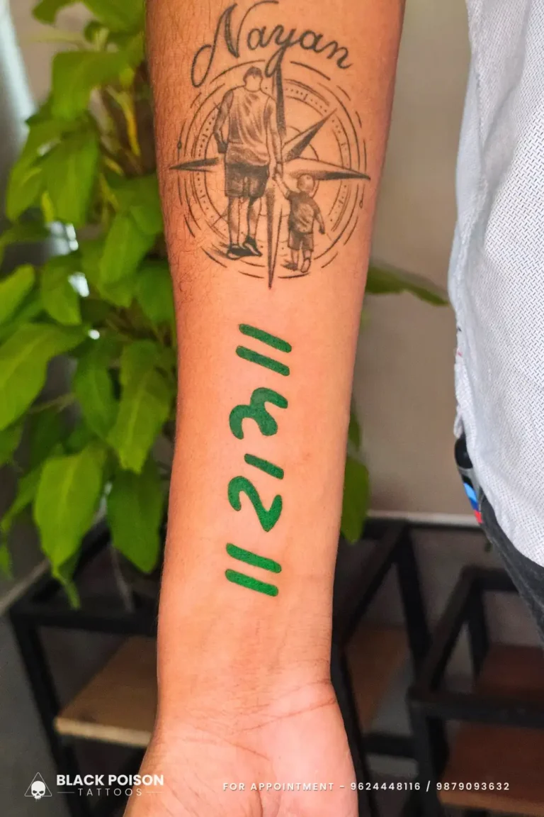 A meaningful tattoo featuring the "Ram" mantra in bold green Sanskrit script below a fine-line silhouette of a father and son walking toward a compass by Black Poison Tattoo Studio Ahmedabad.