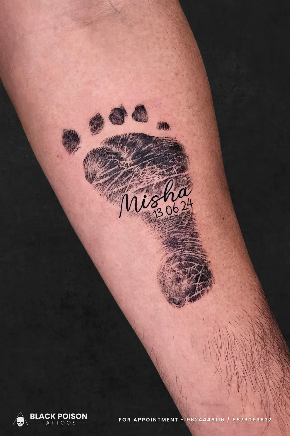 Black and grey realistic baby footprint tattoo with a cursive name and birth date on the forearm, done at Black Poison Tattoo Studio in Ahmedabad.