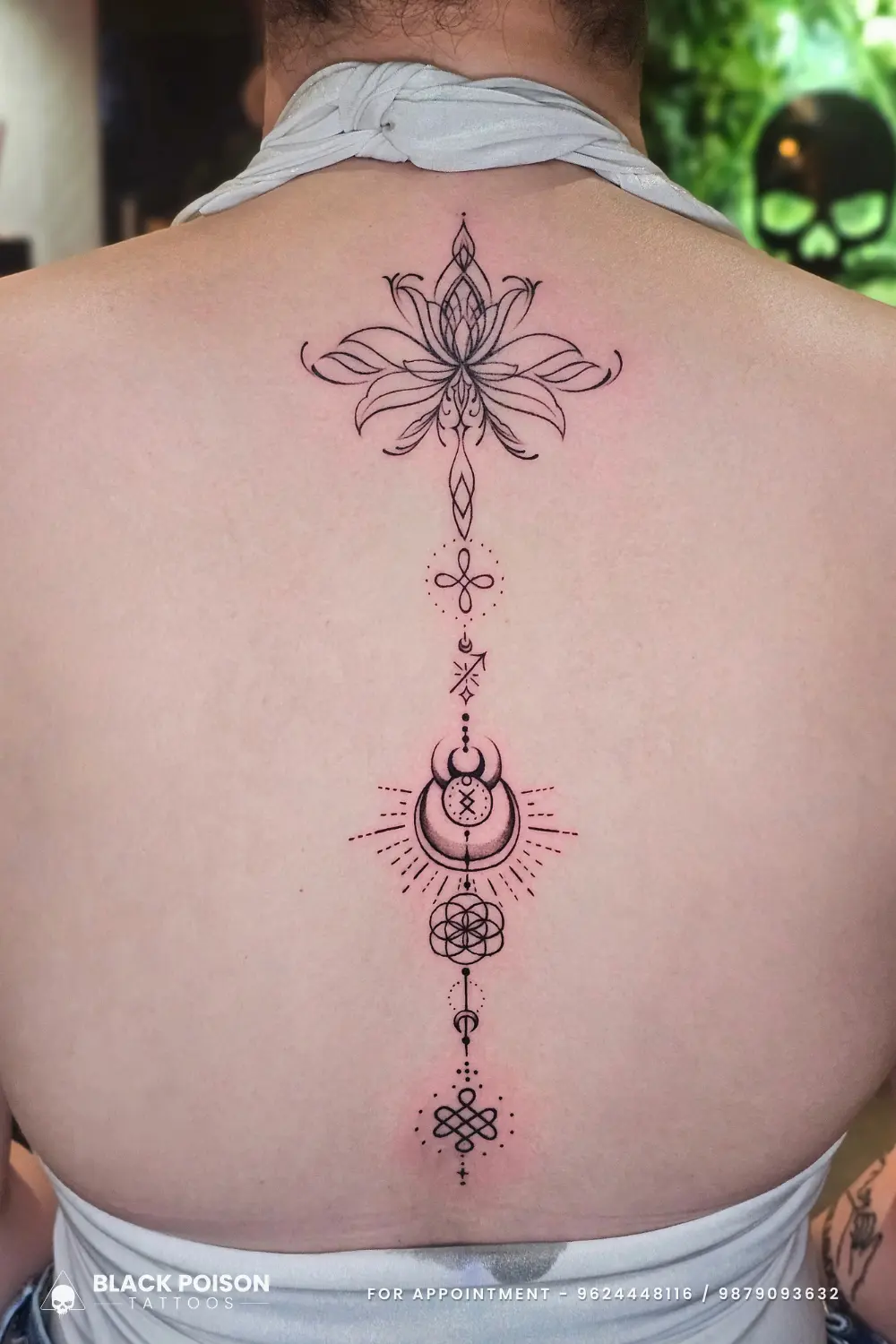 A custom fine line ornamental spine tattoo for women featuring an unalome, lotus, and sacred geometry, crafted at Black Poison Tattoo Studio in Ahmedabad.