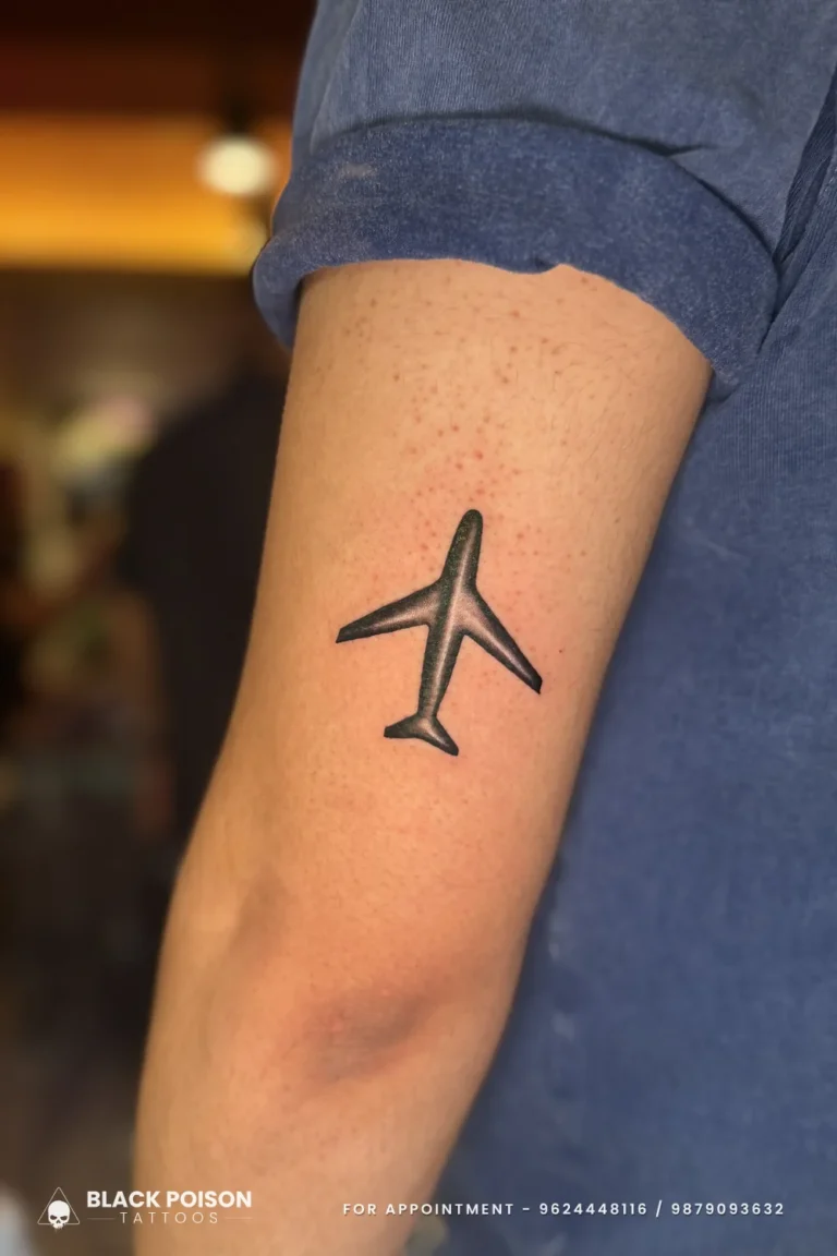 Solid black airplane silhouette tattoo on the back of the upper arm at Black Poison Tattoo Studio, Ahmedabad
