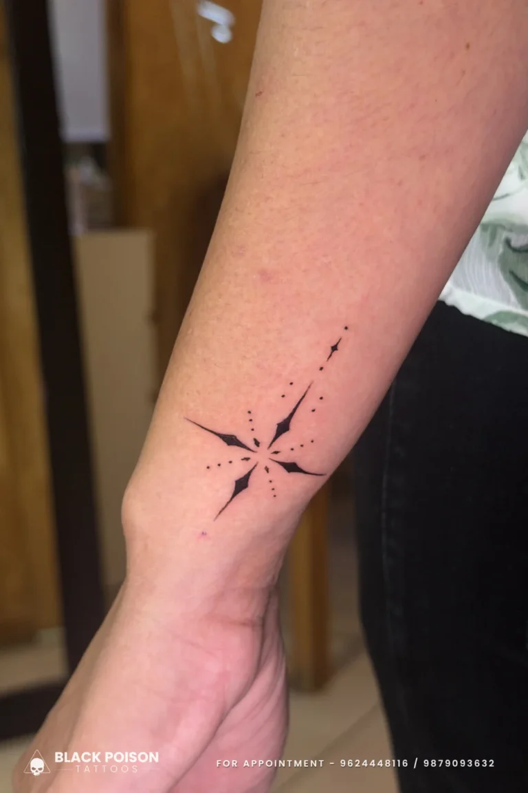Bold black north star compass tattoo with a dotted axis on the inner forearm at Black Poison Tattoo Studio, Ahmedabad