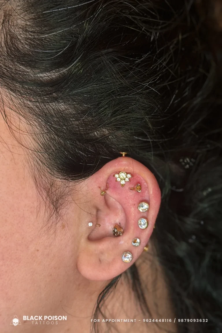 Curated ear with a forward helix crown cluster, tragus stud and crystal lobe studs at Black Poison Tattoo Studio, Ahmedabad